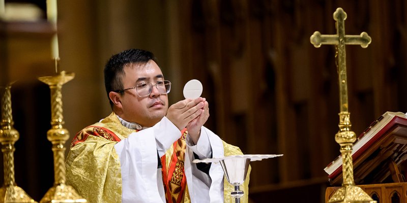 Ein Priester hält eine Hostie in seinen Händen