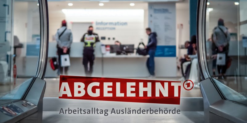 KI-generiertes Bild einer Behörde mit Antragstellern und Sicherheitspersonal, im Vordergrund der Schriftzug "Abgelehnt"