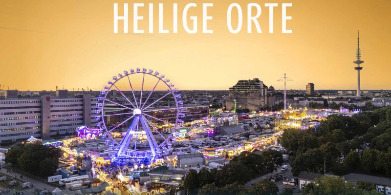 das Hamburger Volksfest mit Riesenrad, Fahrgeschäften und Fernsehturm mit Schriftzug "Heilige Orte" darüber