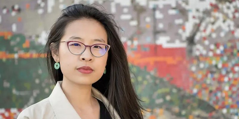 Porträtaufnahme von Liya Yu, die vor einm farbigen Hintergrund