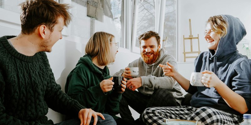 jeweils zwei junge Frauen und Männer sitzen locker beim Kaffee zusammen und lachen herzlich über das, worüber sie sprechen