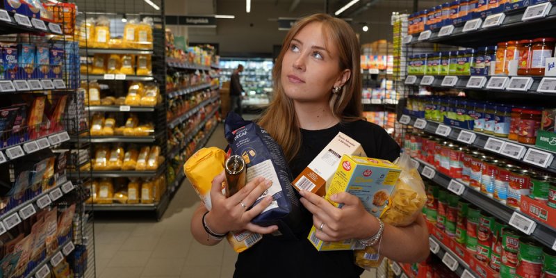 hr-Autorin Malina Homann zwischen Supermarkregalen mit verschiedenen Lebensmitteln im Arm