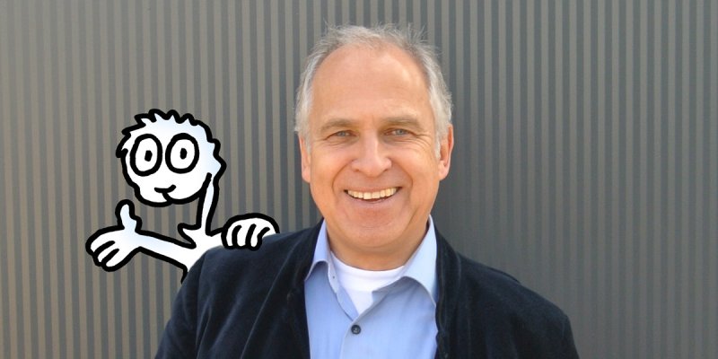 der lachende Werner Tiki Küstenmacher mit einer freundlichen Comic-Figur, die über seine Schulter winkt